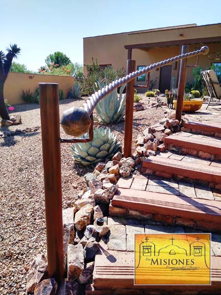 one steel twisted bar with ball endcaps curved to outdoor garden stairway as a handrail 